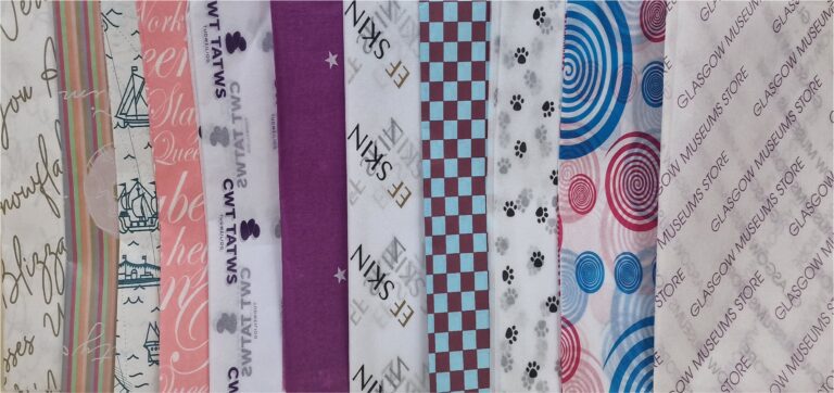 A sel4ection of acid free branded tissue papers in lots of designs showing a rainbow of colours.